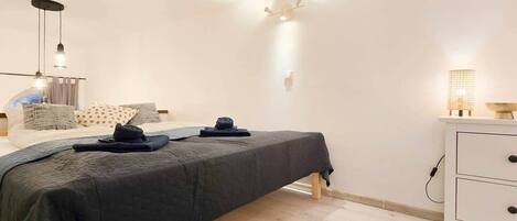 Un dormitorio con cama, mesita de noche, lámpara y una lámpara de pared.