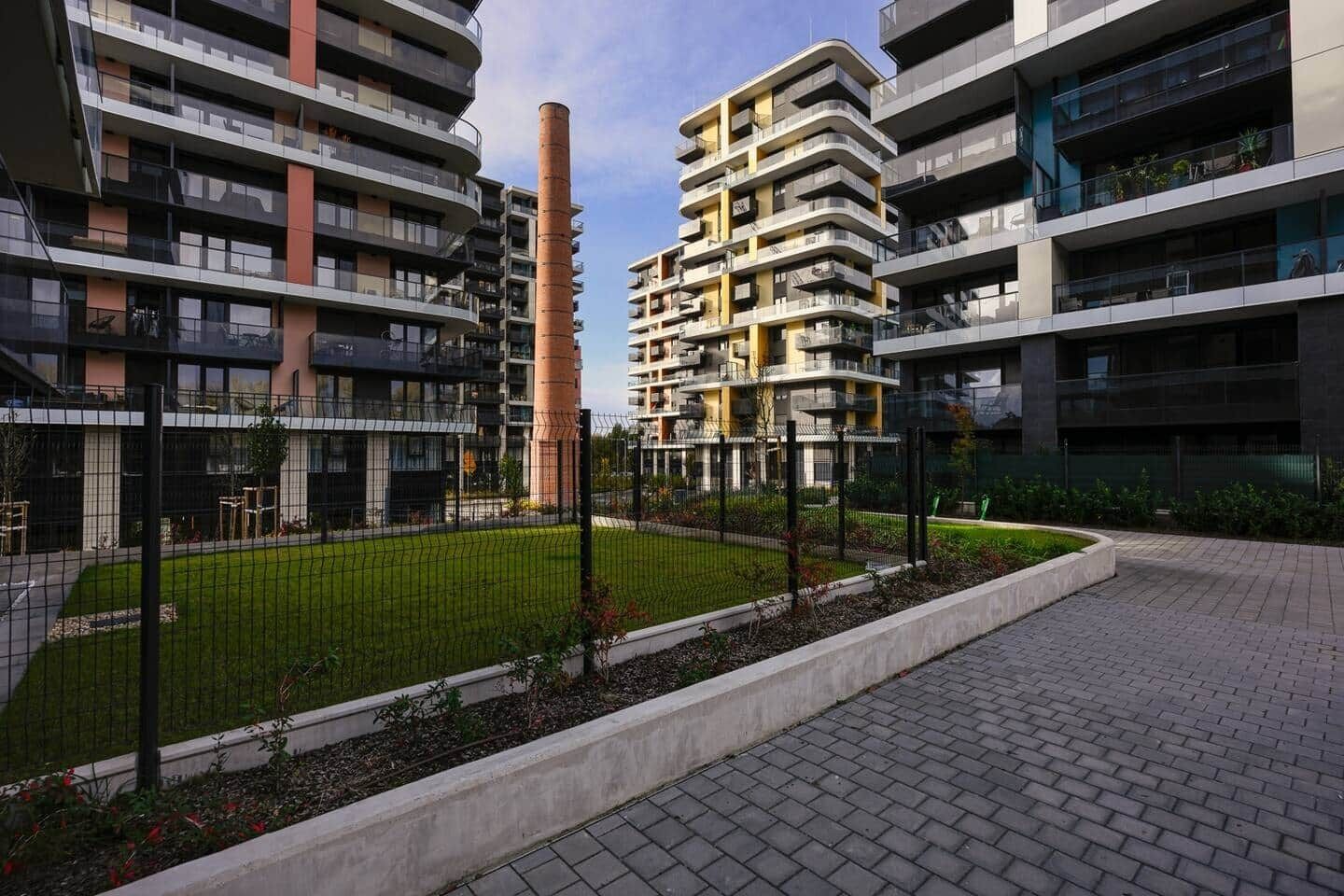 A modern residential building with multiple balconies, a central courtyard, and a brick pathway.