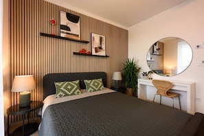 A hotel room with a bed, bedside tables, a desk, a chair, a round mirror, and a potted plant. - IMCT - OpenSky Terrace with free parking (Budapest)