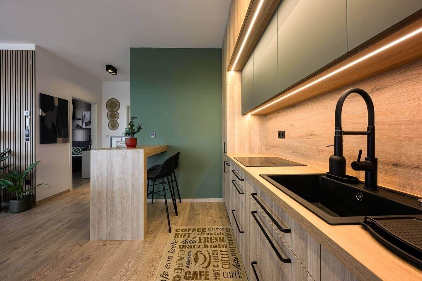 A modern kitchen with a central island, a black sink, and wooden cabinetry.