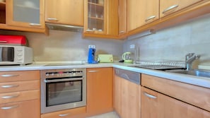 Una cucina con mobili in legno, un forno a microonde, una macchina da caffè, un bollitore e una lavastoviglie.