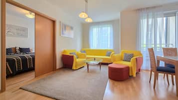 Ein Wohnzimmer mit einer Sofagarnitur, einem Couchtisch und einem Essbereich mit Stühlen.