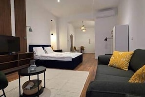 A modern hotel room with a bed, a sofa, a TV, and a desk. - IMCT - Masa Apartman 3 Budapest (Budapest)