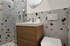 A bathroom with a shower, a sink with a mirror, and a toilet. - IMCT - Masa Apartman 3 Budapest (Budapest)