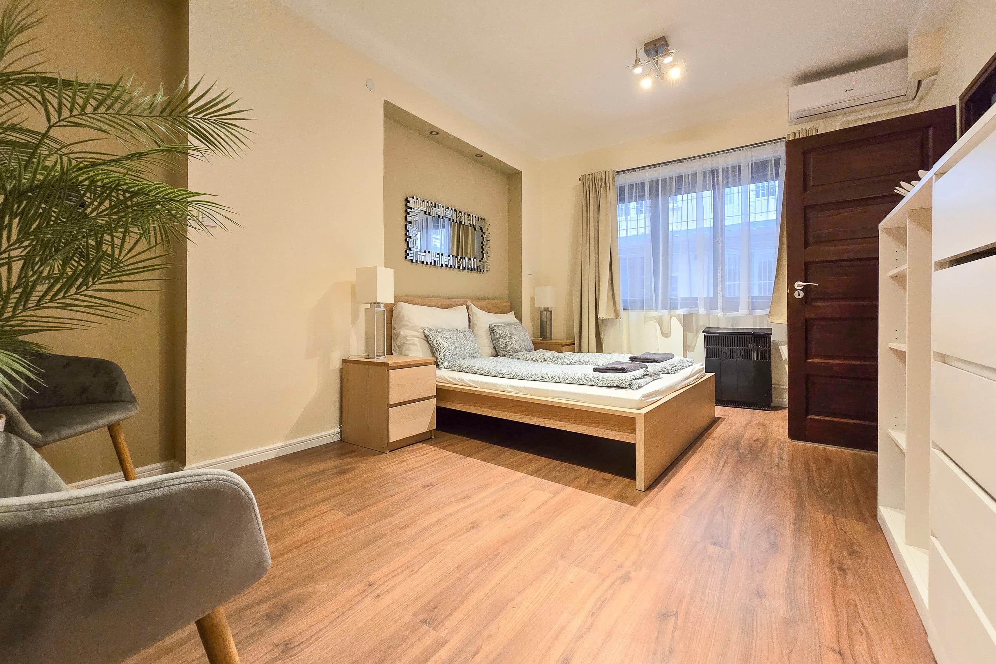 A bedroom with a bed, bedside tables, a lamp, a plant, and a wardrobe.
