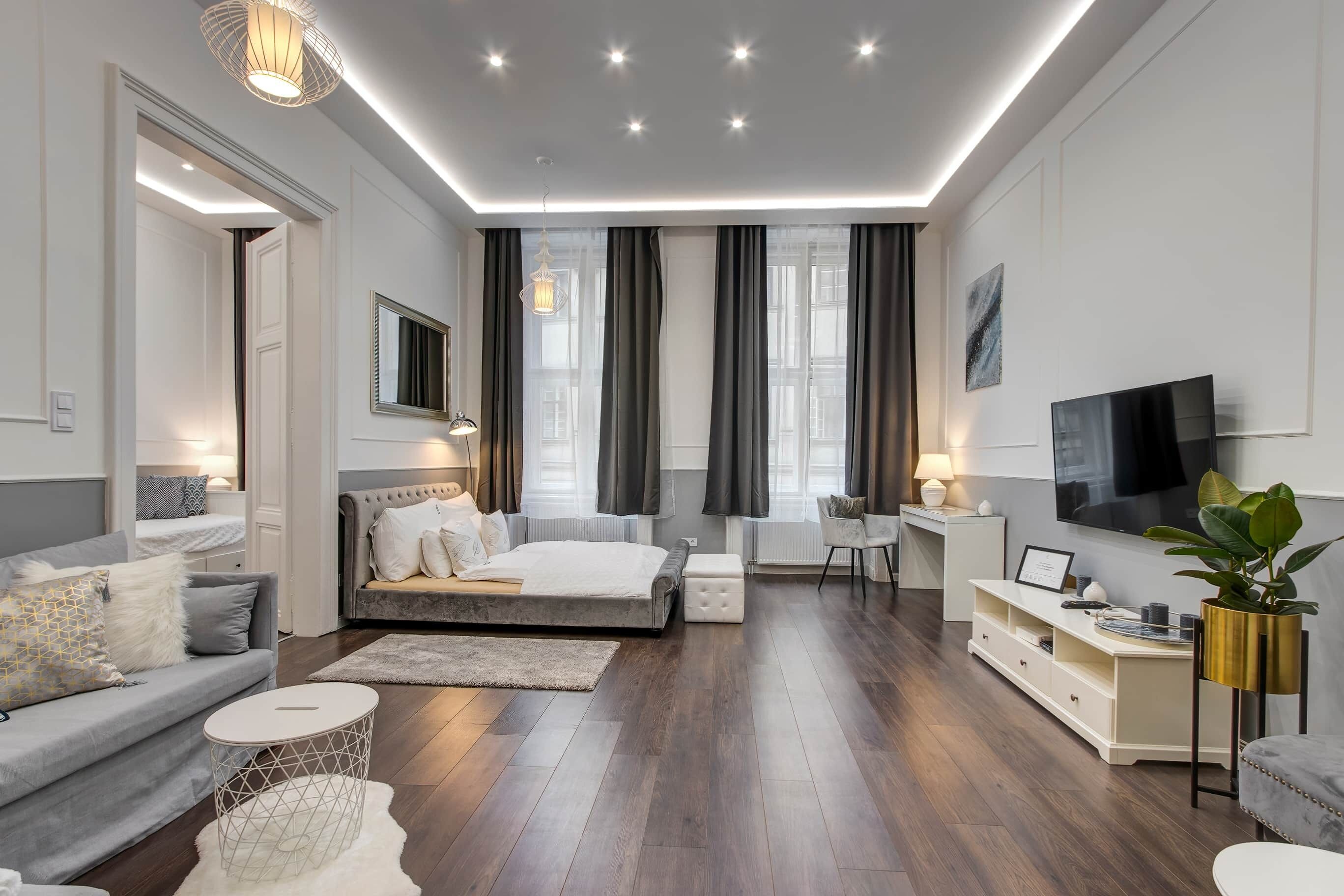 A modern bedroom with a bed, a sofa, a TV, and a desk.