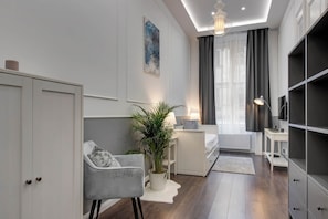 A modern living room with a sofa, a coffee table, a potted plant, and a television. - IMCT - Semmelweis Apartment A (Budapest)