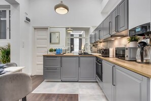 A modern kitchen with grey cabinetry, a wooden countertop, and a built-in oven. - IMCT - Semmelweis Apartment A (Budapest)