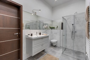 A modern bathroom with a wooden door, a vanity with a mirror, a shower, and a toilet. - IMCT - Semmelweis Apartment A (Budapest)