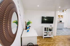 A modern living room with a flat-screen TV, a white console table, and a herringbone-patterned floor. - IMCT - Tailor Apartment in the Center (Budapest)