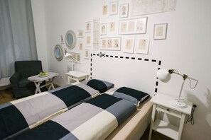 A hotel room with two beds, a desk, a chair, and a wall adorned with framed sketches. - IMCT - Tailor Apartment in the Center (Budapest)