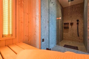 A sauna room with a wooden bench, a glass door, and a stone wall. - IMCT - Urban Jungle Apartments 05 (Budapest)