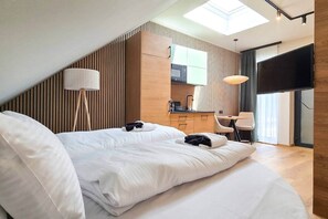 A modern hotel room with a bed, a desk, and a kitchenette. - IMCT - Urban Jungle Apartments 05 (Budapest)