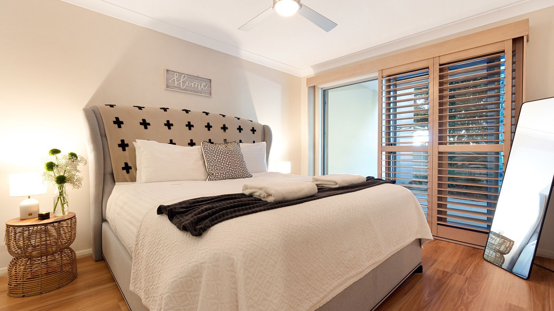 A bedroom with a bed, bedside table, lamp, and a window with blinds.