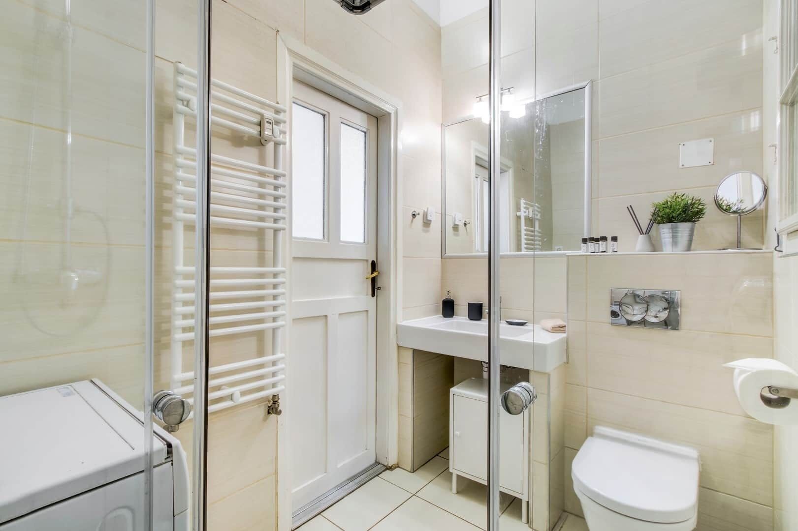 A modern bathroom with a glass shower enclosure, a white toilet, a sink with a mirror, and a towel rack.