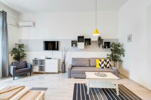 A modern living room with a sofa, a coffee table, a TV, and a yellow pendant light. - IMCT - Panorama Apartment Synagogue (Budapest)