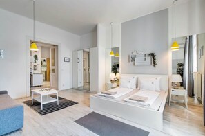Een moderne hotelkamer met een bed, nachtkastjes, een zithoek en uitzicht op de keuken.