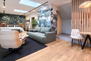 A modern living room with a sofa, armchair, and a dining table. - IMCT - Urban Jungle Apartments 09 (Budapest)