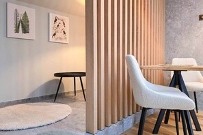 A modern interior with a wooden partition, a round table, and two chairs. - IMCT - Urban Jungle Apartments 09 (Budapest)