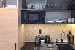 A modern kitchen with a microwave, coffee maker, and a sink. - IMCT - Urban Jungle Apartments 09 (Budapest)