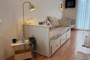 A cozy bedroom with a bed, bedside table, lamp, and a small plant. - LB - Balaton Nova Apartment-Beachfront (Siófok)