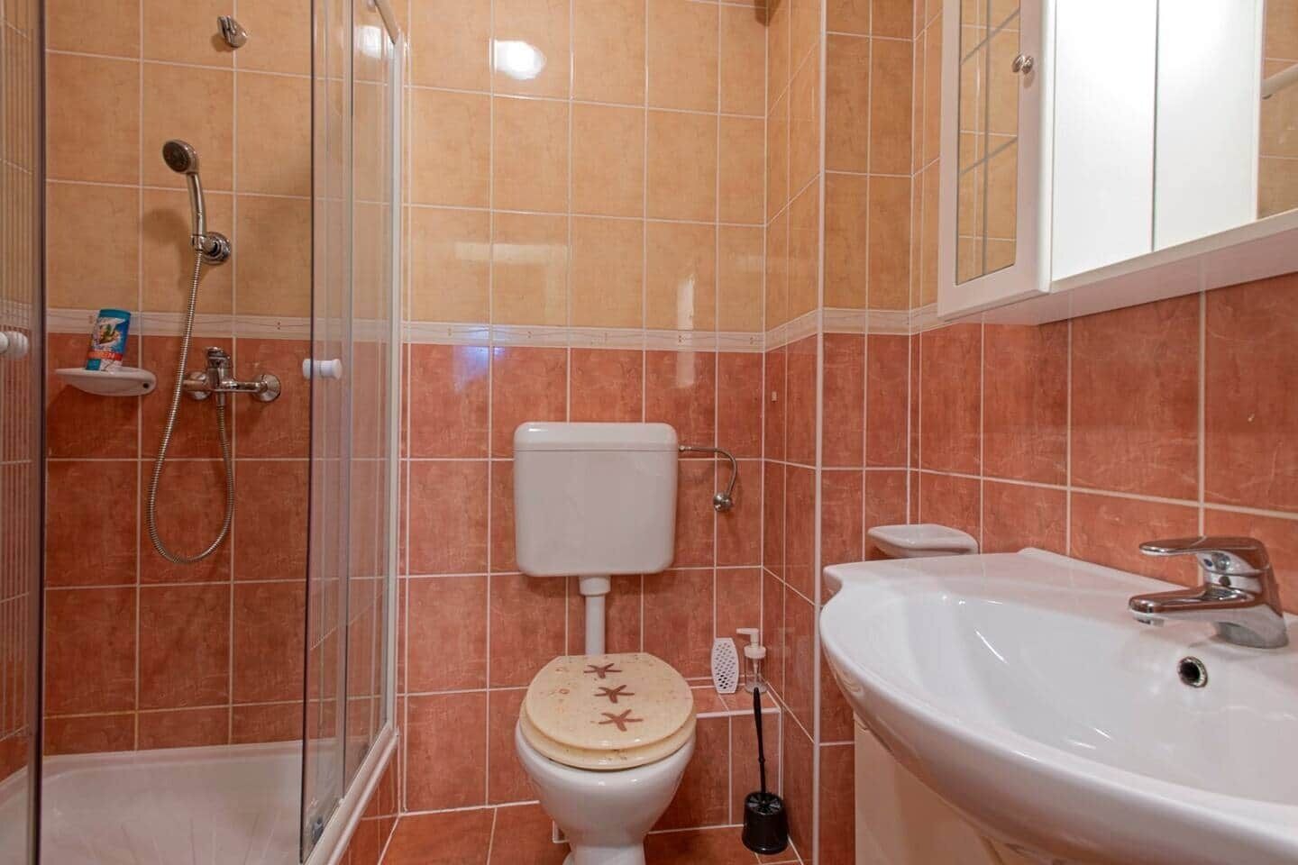 Et badeværelse med brusebad, toilet og vask.