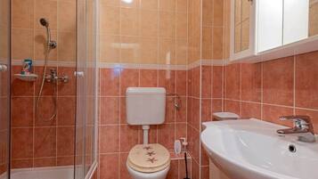 Et badeværelse med brusebad, toilet og vask.