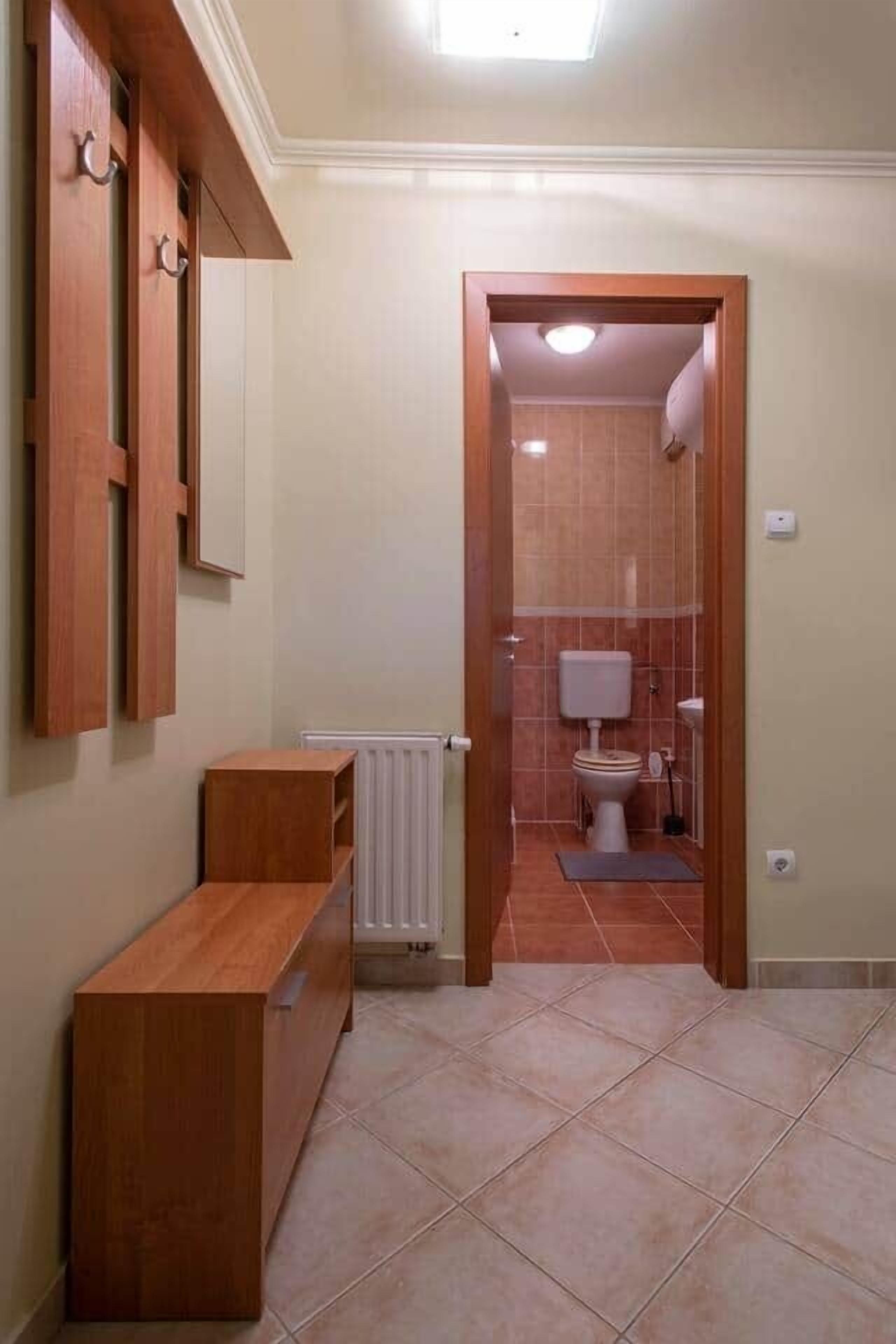 Un corridoio che conduce a un bagno con il water, uno specchio e una panca.