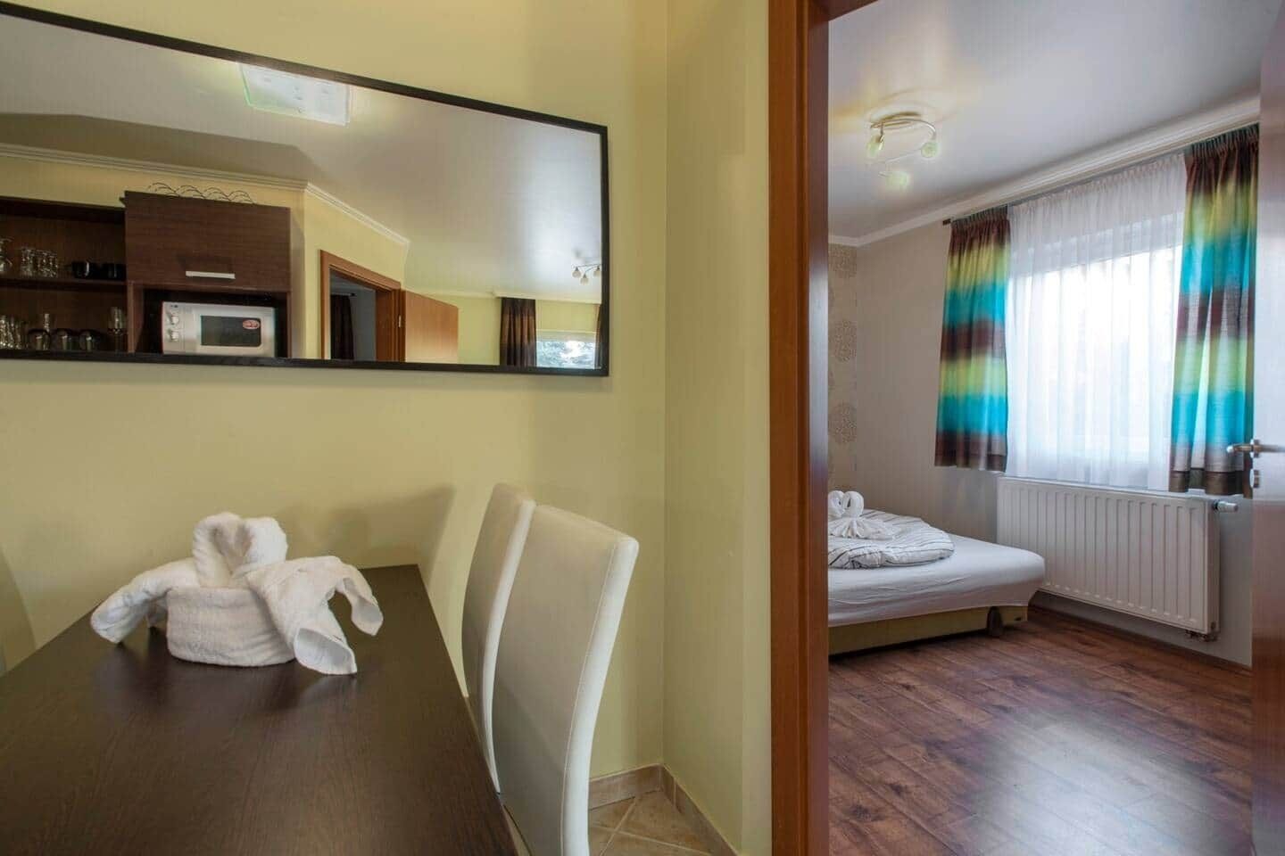 A hotel room with a dining area, a bed, and a view of the outside.