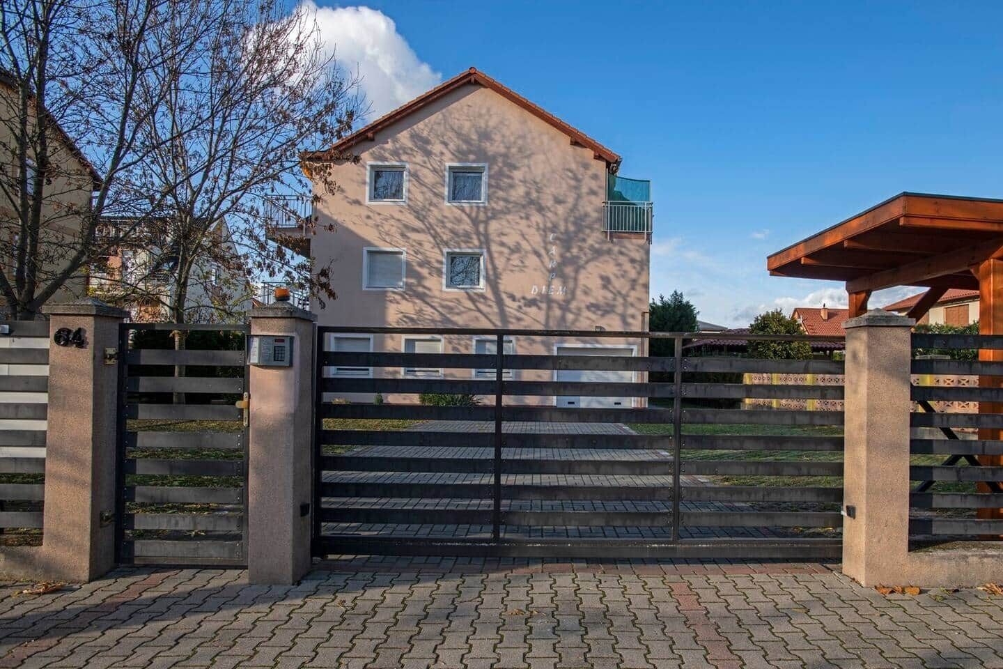A gated entrance to a building with a paved driveway and a clear sky.