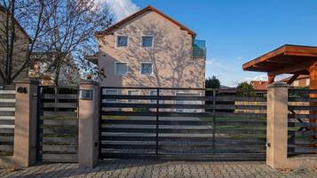 A gated entrance to a building with a paved driveway and a clear sky.