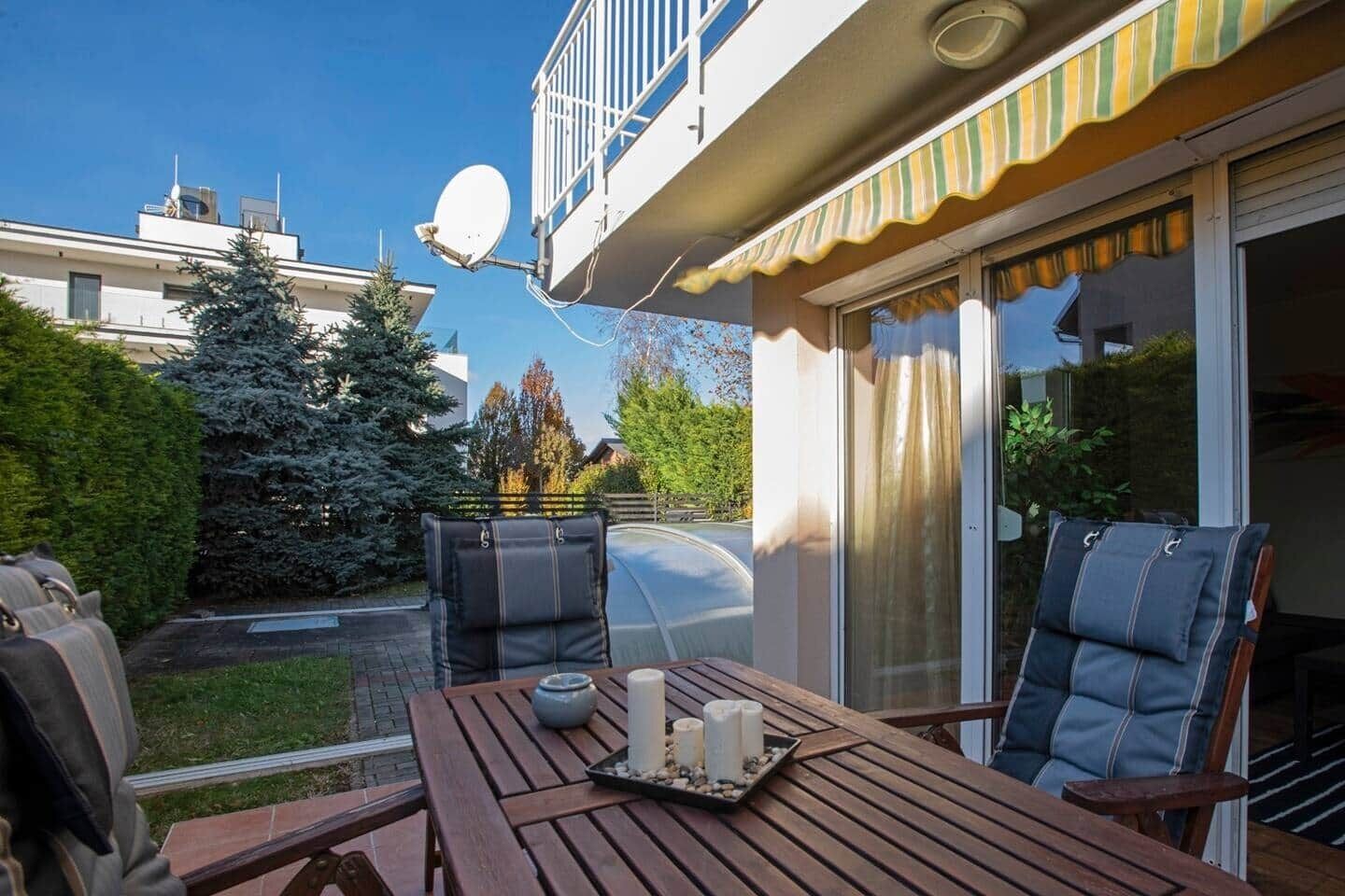 A patio with a table, two chairs, a barbecue grill, and a satellite dish.