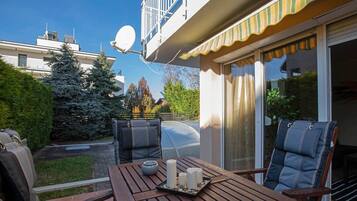 A patio with a table, two chairs, a barbecue grill, and a satellite dish.