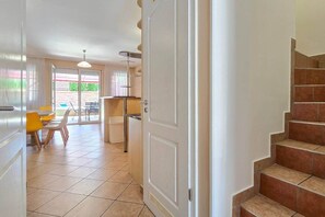 A hallway leading to a dining area with a table and chairs, a staircase, and a door. - LB - Horváth Vendégház 2 (Zamárdi)