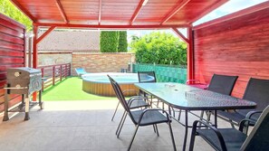An outdoor patio with a barbecue grill, a hot tub, and a dining table with chairs. - LB - Horváth Vendégház 2 (Zamárdi)