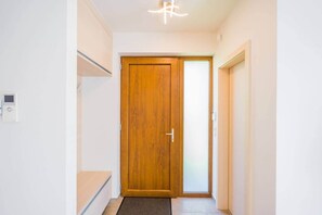 Ein Flur mit einer Holztür, einem Thermostat und einer Leuchte.