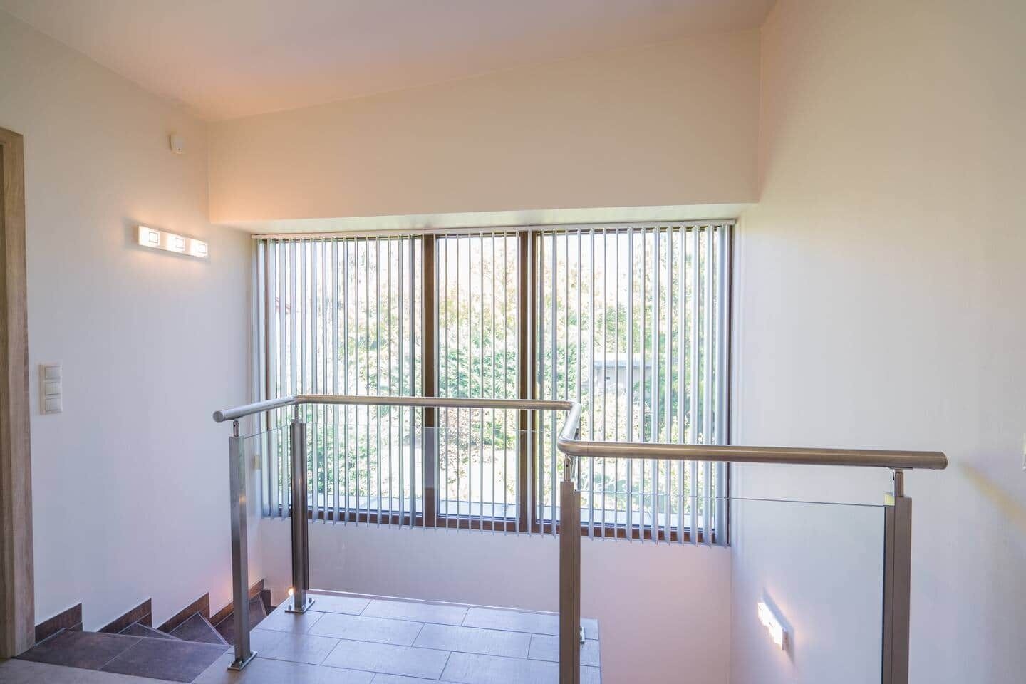 Una escalera con barandas metálicas que lleva a un balcón con vistas a la vegetación.