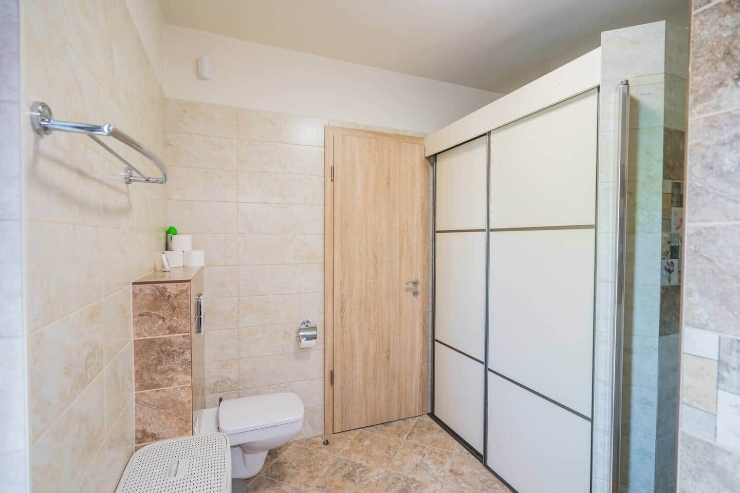 Une salle de bain comprenant des toilettes, un espace douche doté d’une porte en verre et un porte-serviettes.