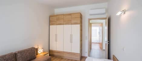Un dormitorio con cama, armario de madera, mesita de noche y sofá.