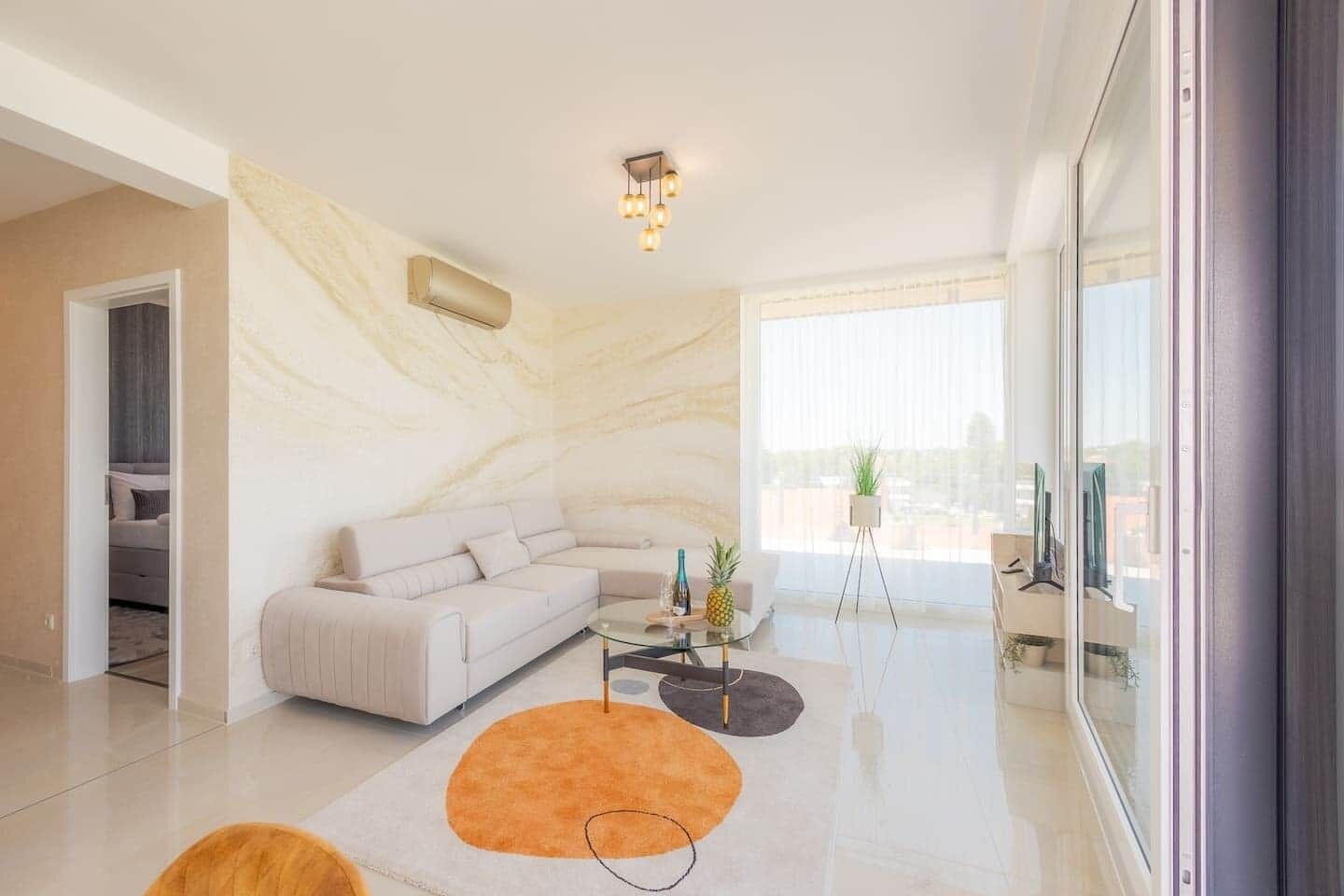 A modern living room with a sofa, coffee table, and a large window with a view.