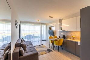 A modern apartment with a living room, dining area, and kitchen. - LB - LelleMarine Apartments A002 (Balatonlelle)