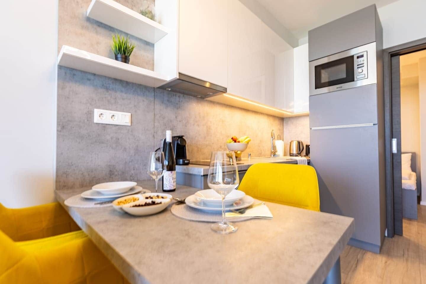 Una cocina moderna con una mesa de comedor preparada para dos personas, un microondas y una cafetera.