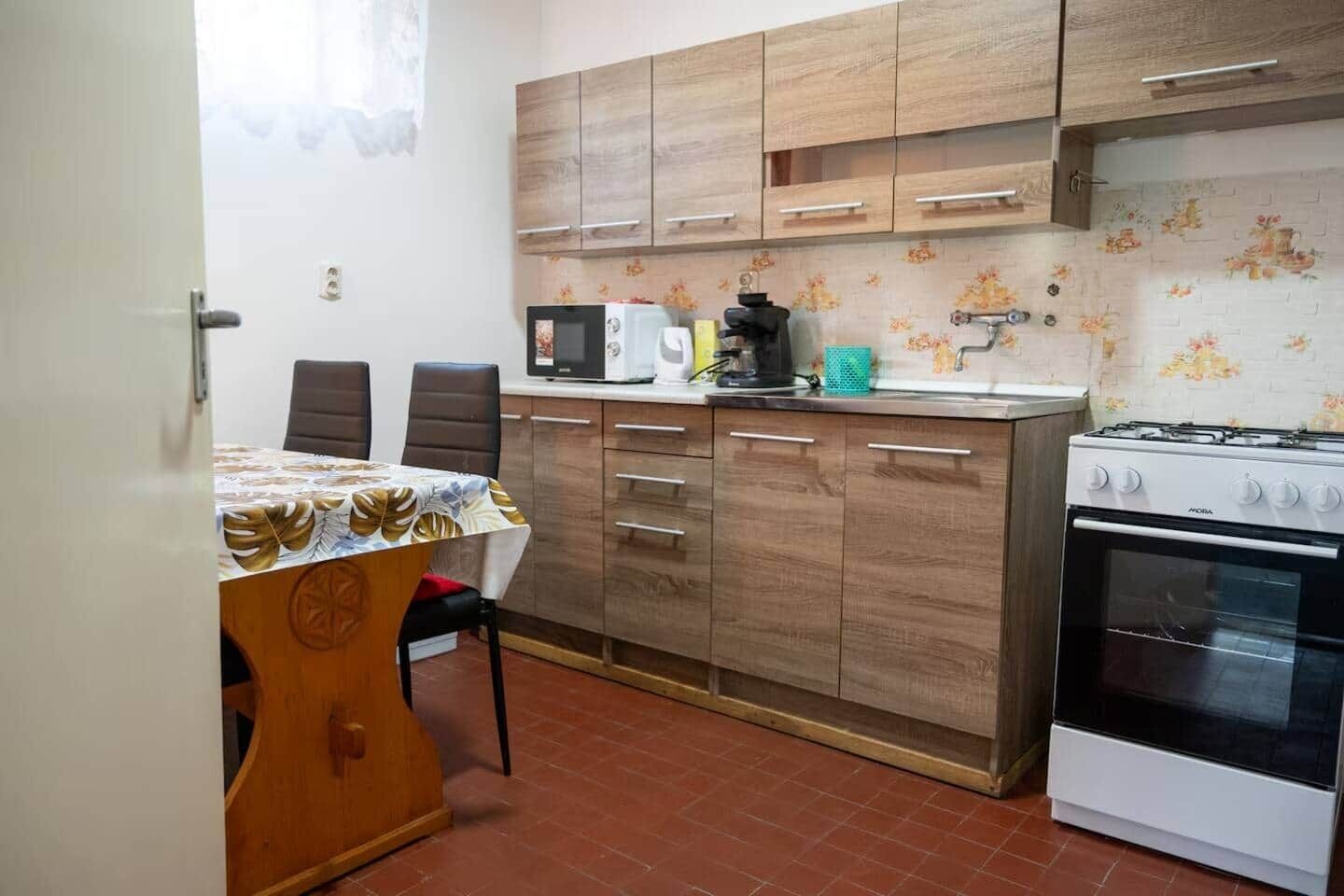 Una cocina compacta con una mesa, sillas, microondas, cafetera y estufa.