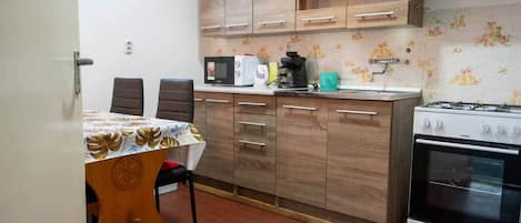 A compact kitchen with a dining table, chairs, a microwave, a coffee maker, and a stove.