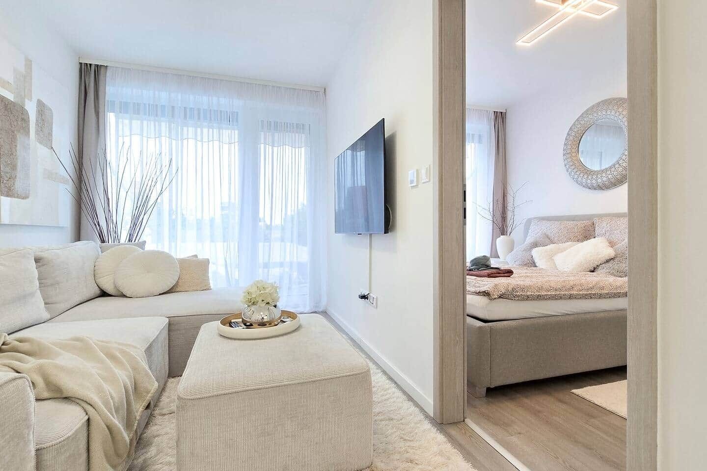 Uma sala de estar moderna com sofá, um banquinho e uma cama com cabeceira.