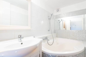A bathroom with a white sink, a bathtub, and a shower. - MidTerm - Chic Soho Apartment near Opera (Budapest)