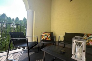 Ein Balkon mit zwei schwarzen Stühlen, einem kleinen Tisch und einem weißen Laternen.