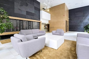 A modern lobby with grey sofas, a white coffee table, and a black and beige wall design. - MidTerm - Rózsa 55 Apartman (Budapest)