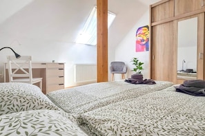 Une chambre à coucher avec un lit, un bureau, une chaise, un radiateur, une fenêtre et un tableau.