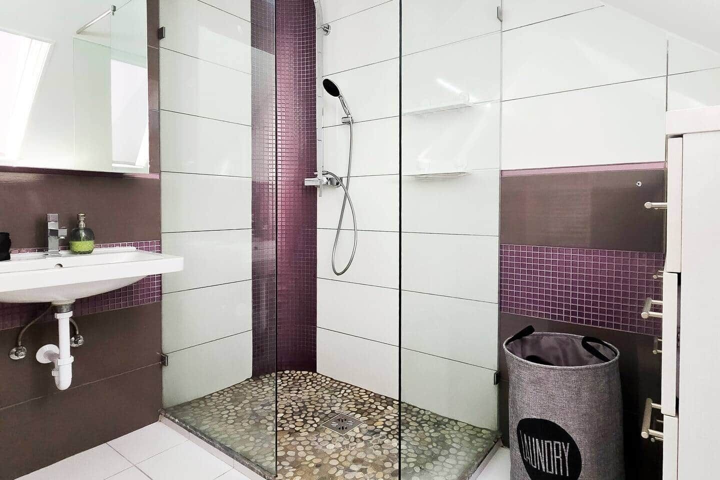 Ein Badezimmer mit Dusche, Waschbecken und Mülleimer.